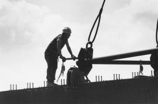 Steelworker joining 100-tonne beams to the concrete supports of the new Burlington Skyway span. Burlington, Ontario