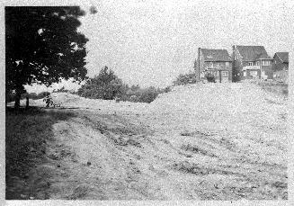 Image shows a road view with some houses on the right.