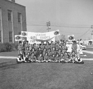 Image shows a group of people posing for a photo on the lawn. they hold a sign that reads: "Lea…