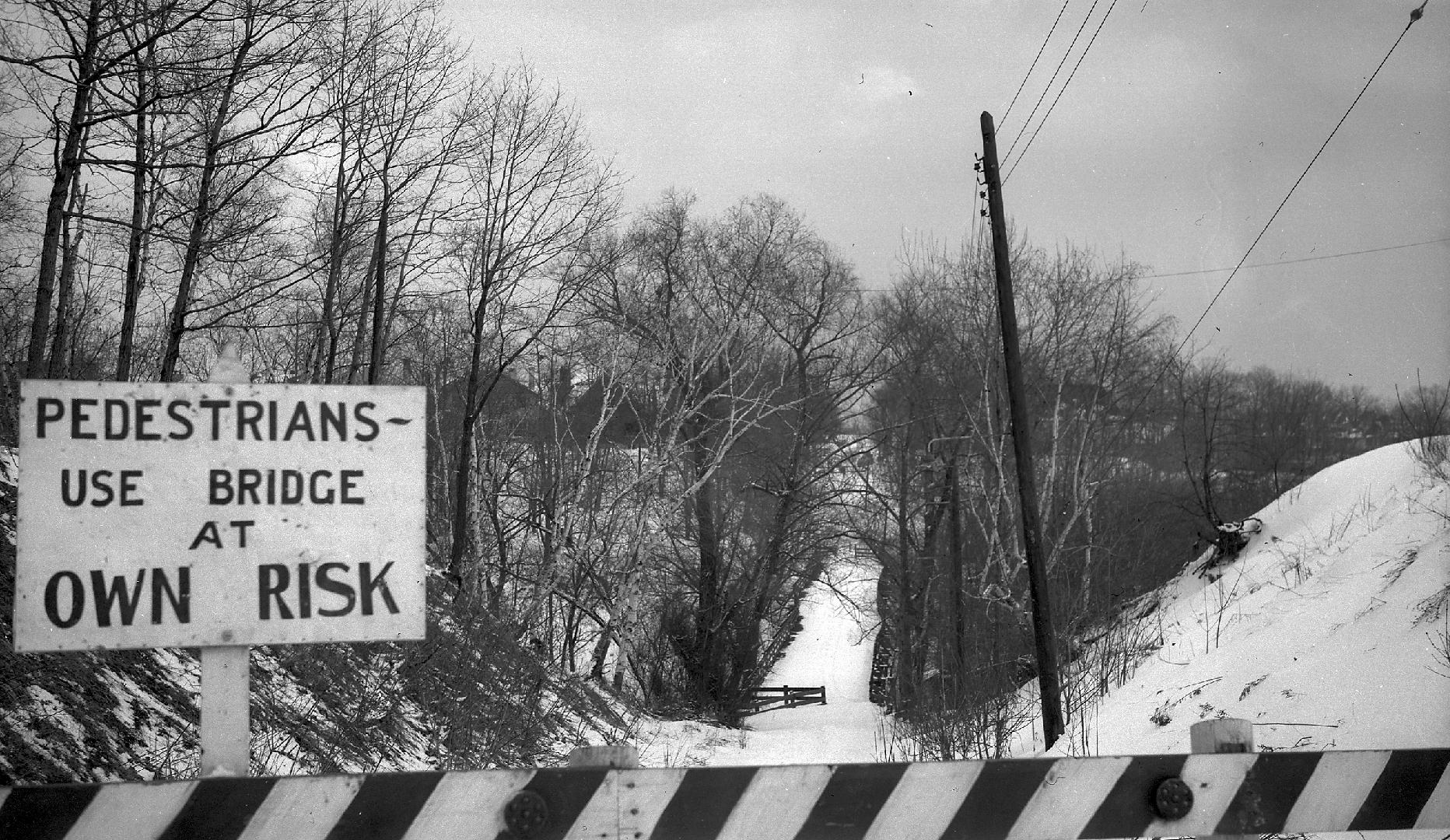 Image shows a river view from the bridge in winter. A sign on the bridge reads: " Pedestrians U…