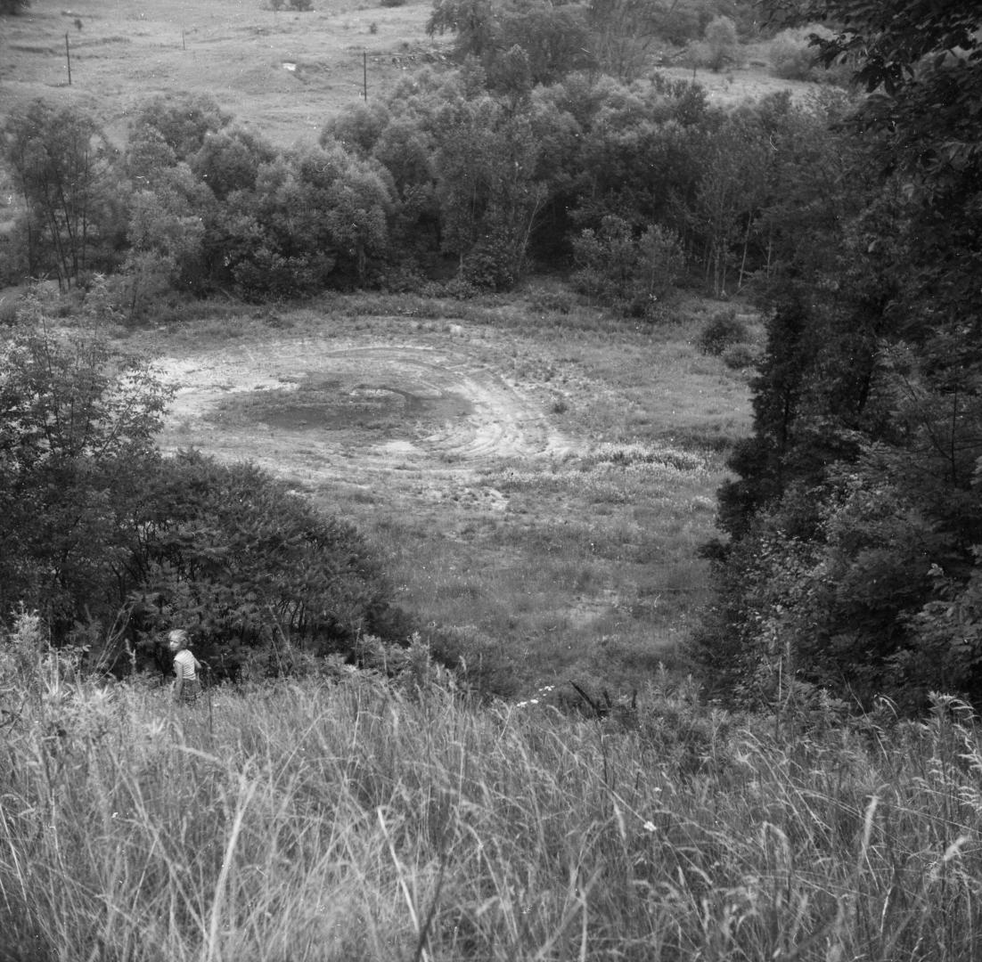 Image shows a site of a ski jump. There are trees around it.