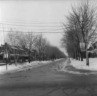 Image shows a street view with some houses on both sides.