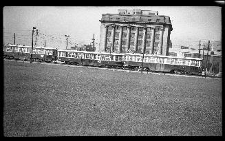 Image shows a multi-floor building with some streetcars in front of it.