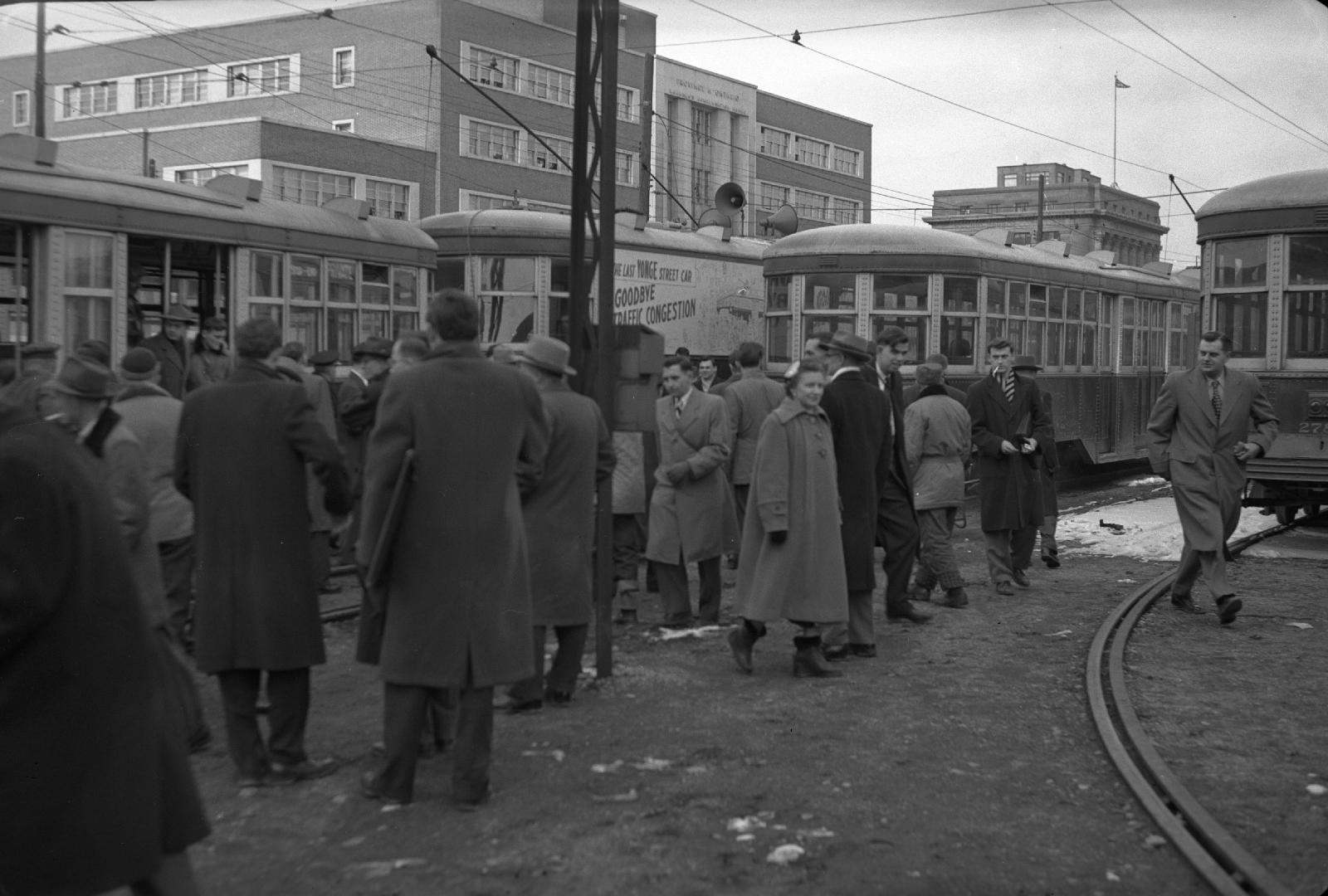 Image shows a number of people at the ferry loop with a few streetcars in the background.