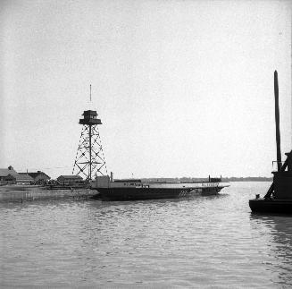 Image shows a boat on the lake with some buildings in the background.