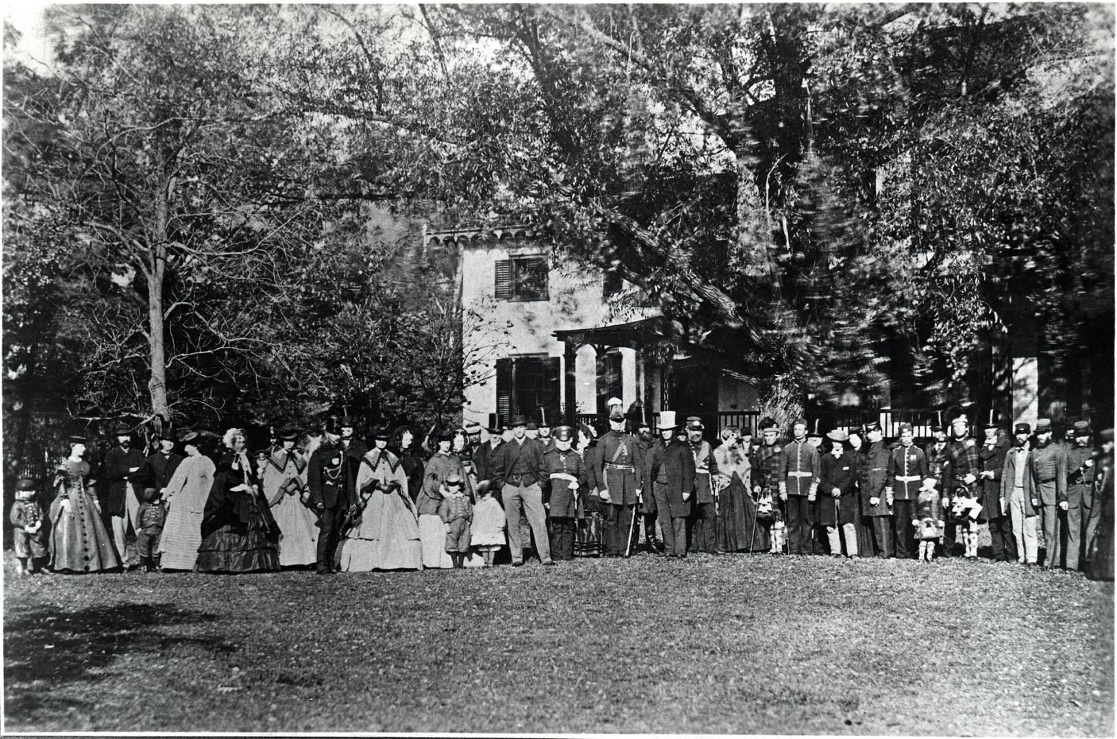 Image shows some military parade participants posing for a photo with a lot of trees in the bac…