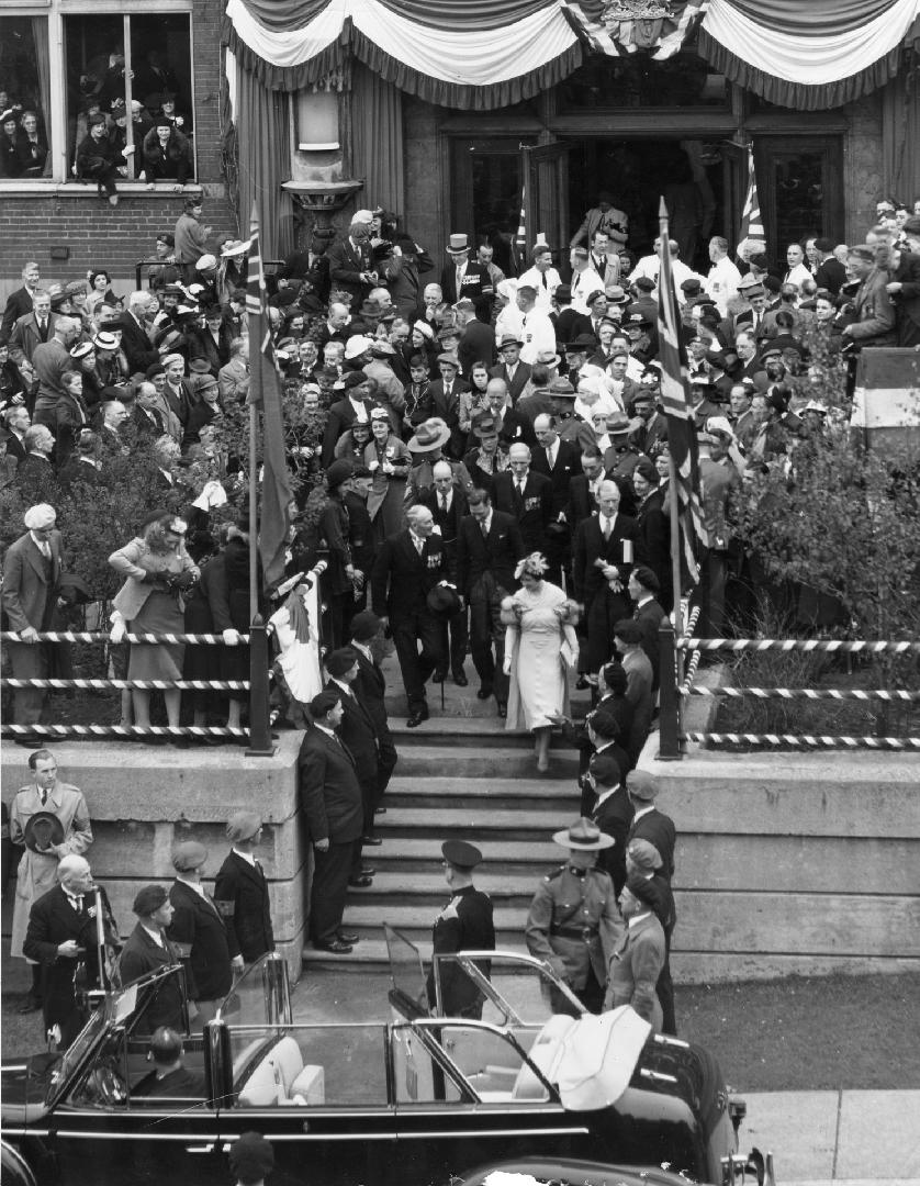 Image shows a lot of people around the stairs where the royals are going down to the automobile…