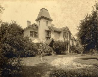 Image shows a two storey residential house surrounded by trees.