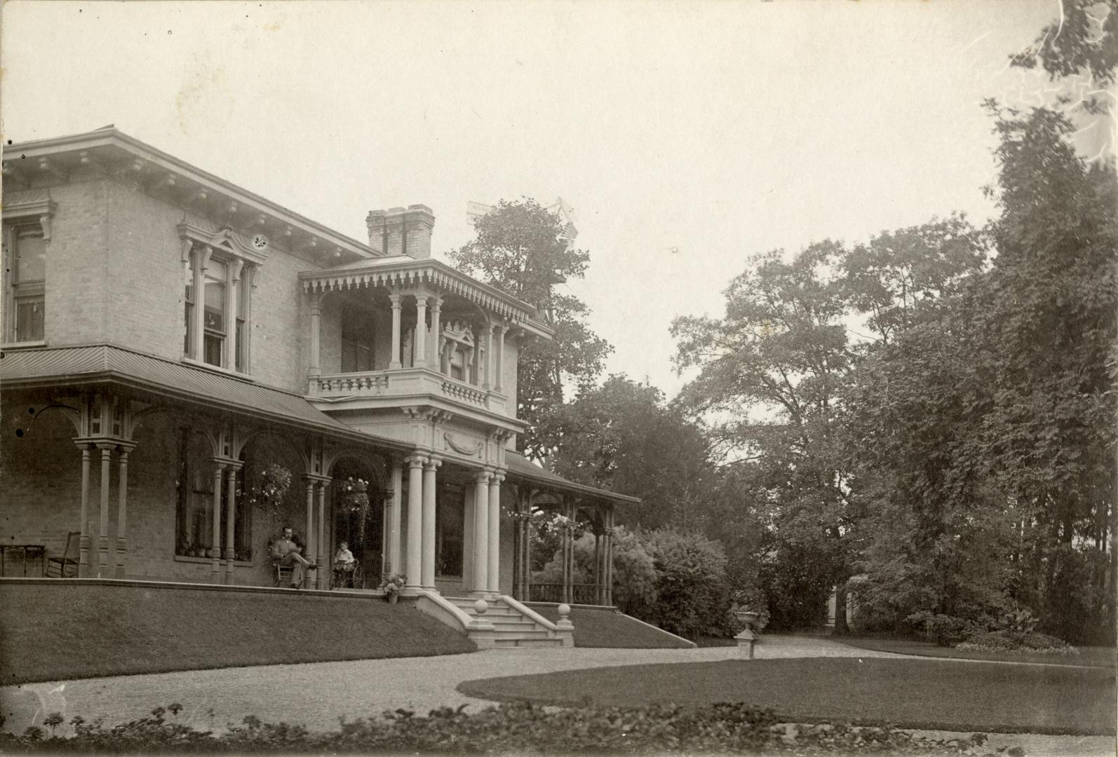 Image shows a limited view of a two storey house with some trees around it.