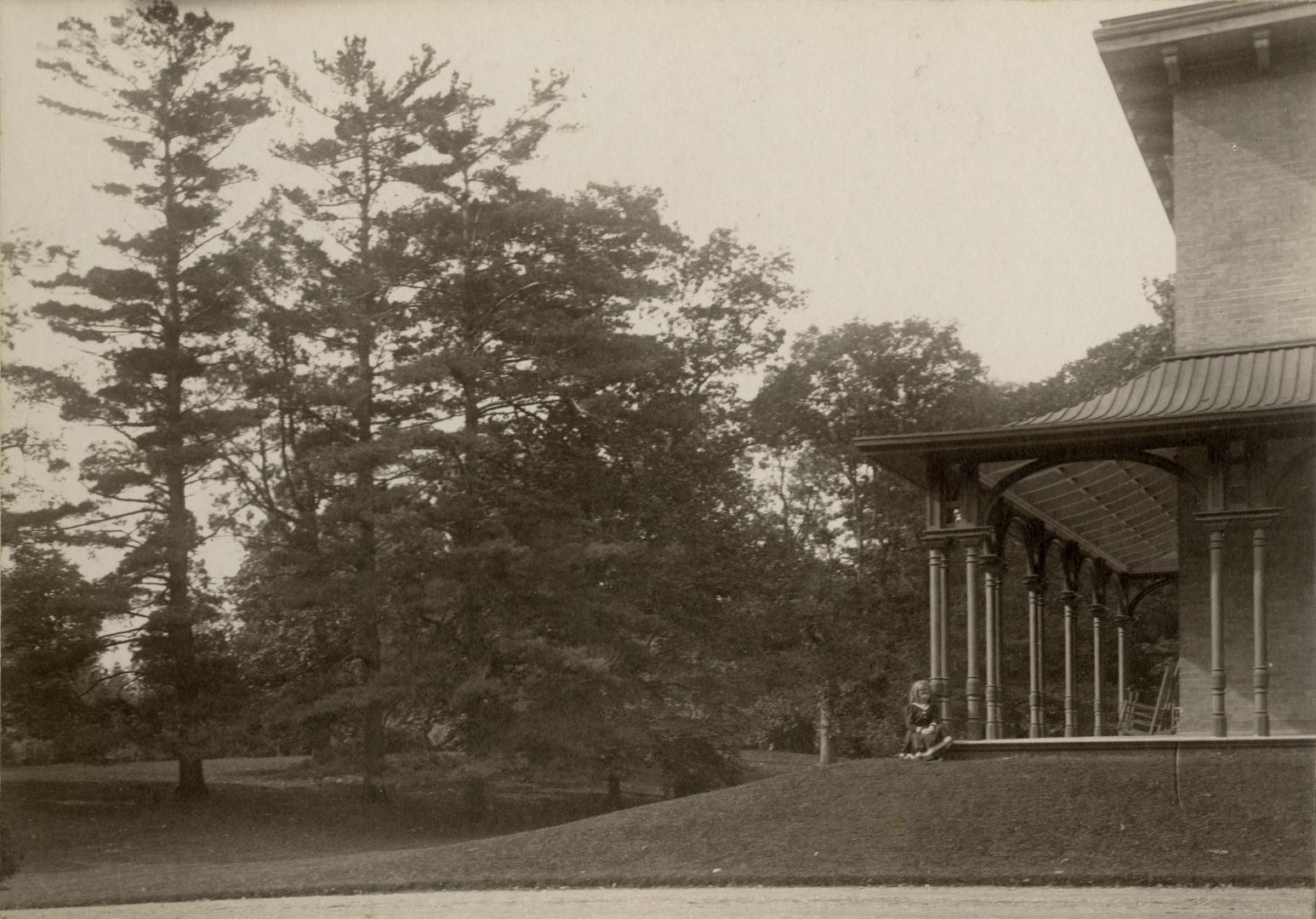 Image shows trees in the park and a very limited view of a house on the left.