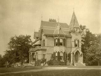 Image shows a two storey residential house with some trees in the background.