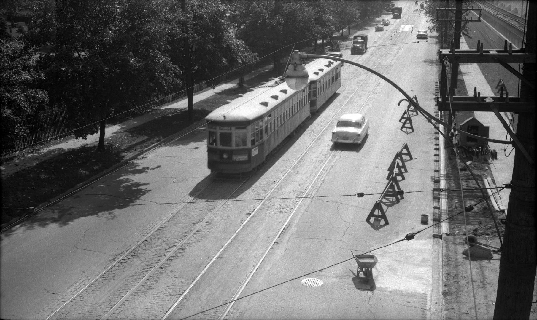 Image shows a street view with a streetcar and some cars on it.