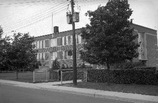 Image shows a street view with a two storey school building along it.