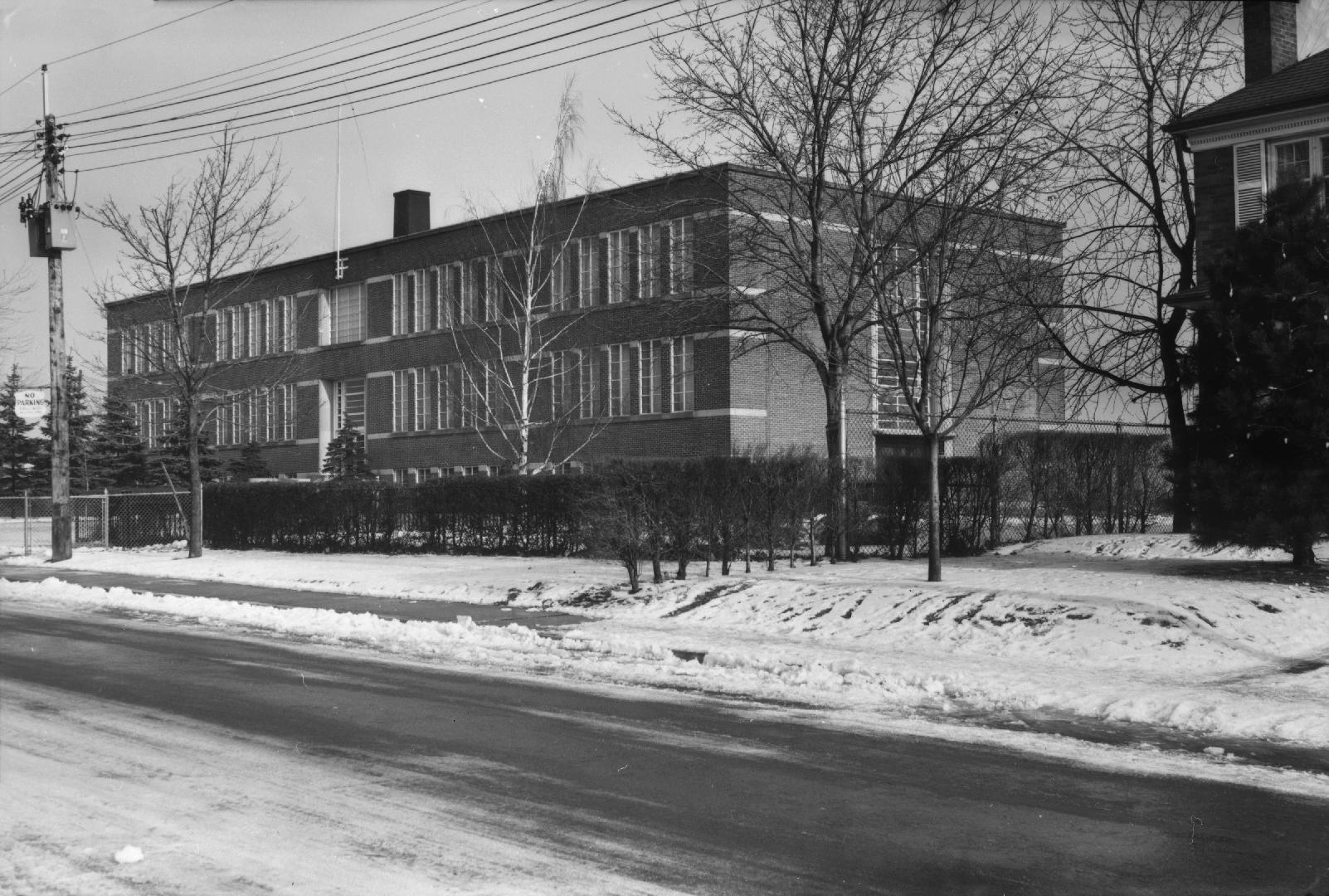 Image shows a street view with a two storey school building along it.