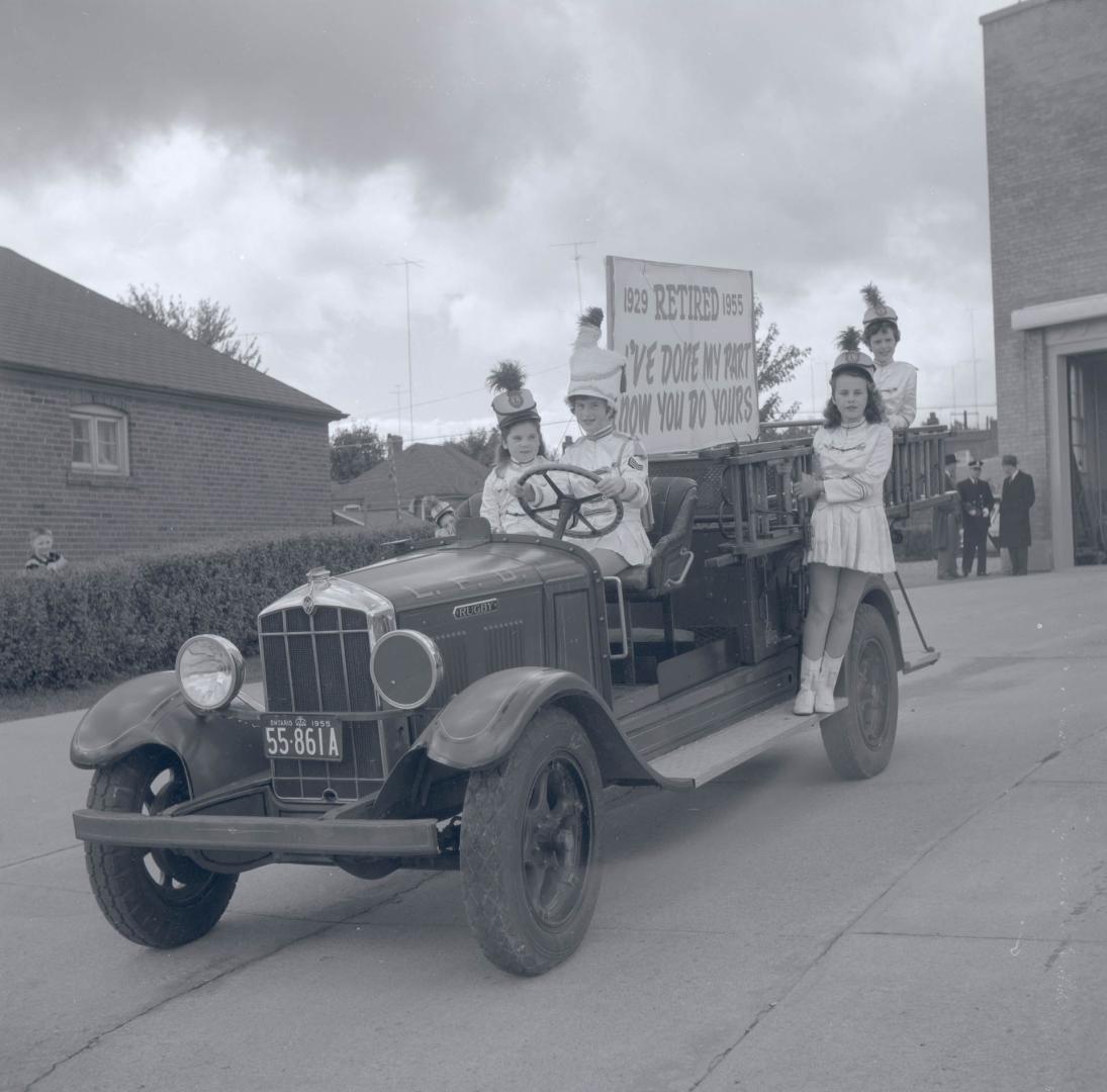 Image shows a few participants of the parade standing/sitting on the vehicle with signs.