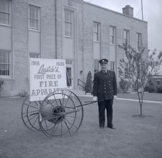 Image shows a participants of the parade posing for a photo beside a sign that reads: "1916 192…