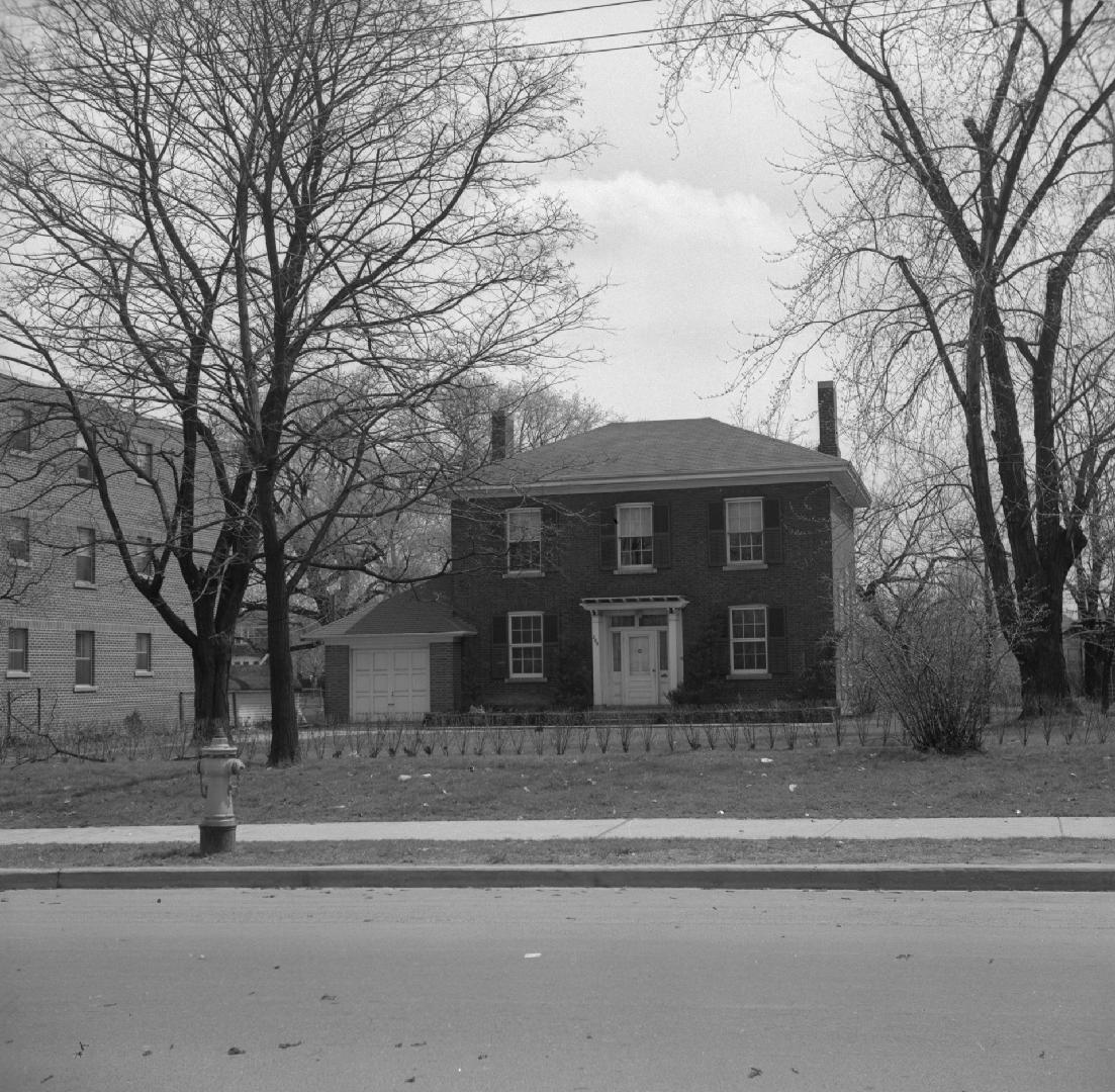 Image shows a house with a few trees on both sides.