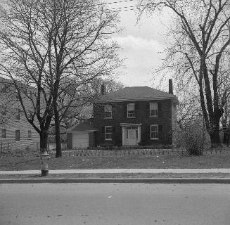 Image shows a house with a few trees on both sides.