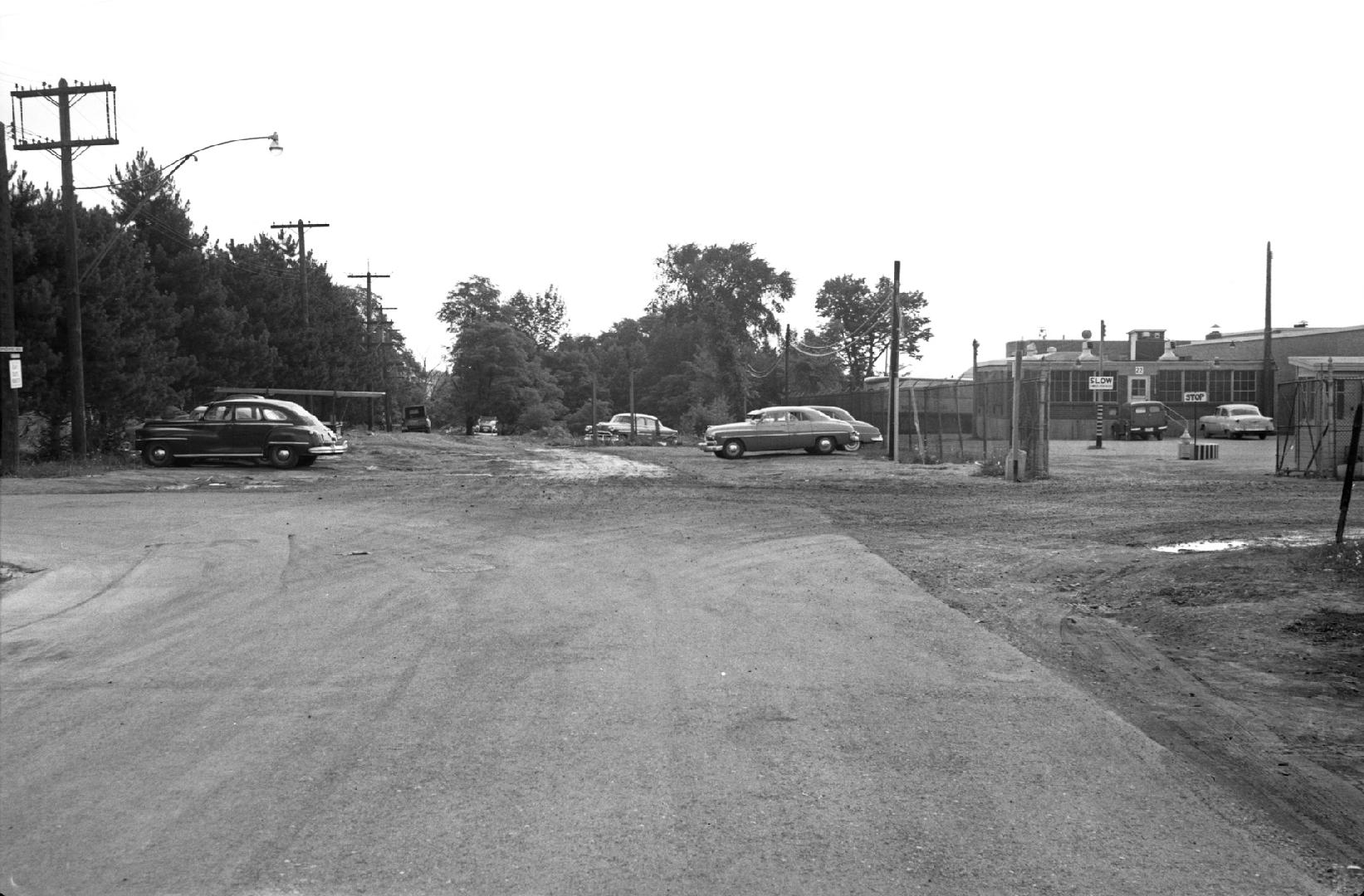 Image shows a street view with some cars parked on the sides.