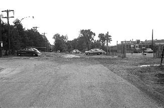 Image shows a street view with some cars parked on the sides.