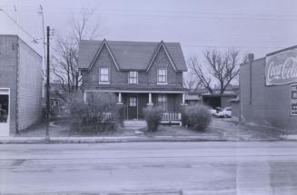 Shows a house between two commercial establishments