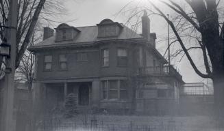 Image shows a two storey residential house with some trees around it.