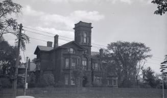 Image shows a three storey house with some trees around it.