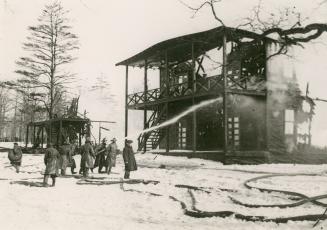 Image shows firefighters pouring water into fire in the barracks.