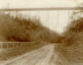 Image shows a road view with a bridge over it.