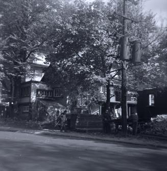 Image shows a limited view of the house. There are a lot of trees in front of it.