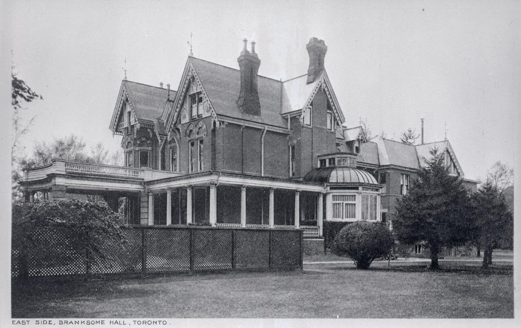 Image shows a three storey house with some trees around it.