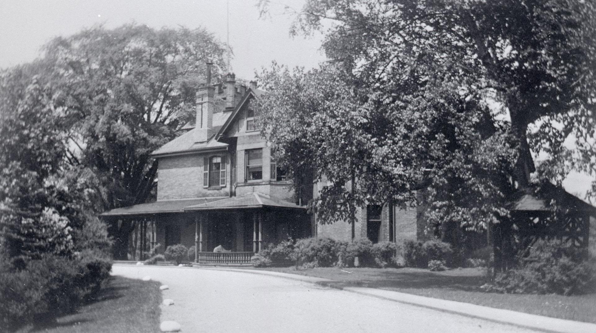 Image shows a limited view of a two storey residential house with a lot of trees on both sides.