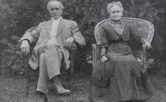 Image shows Martin, Edward, and Mrs Martin posing for a photo by sitting in the armchairs outdo…