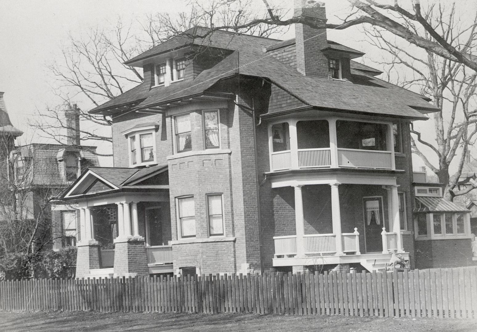 Image shows a three storey residential house with some trees around it.