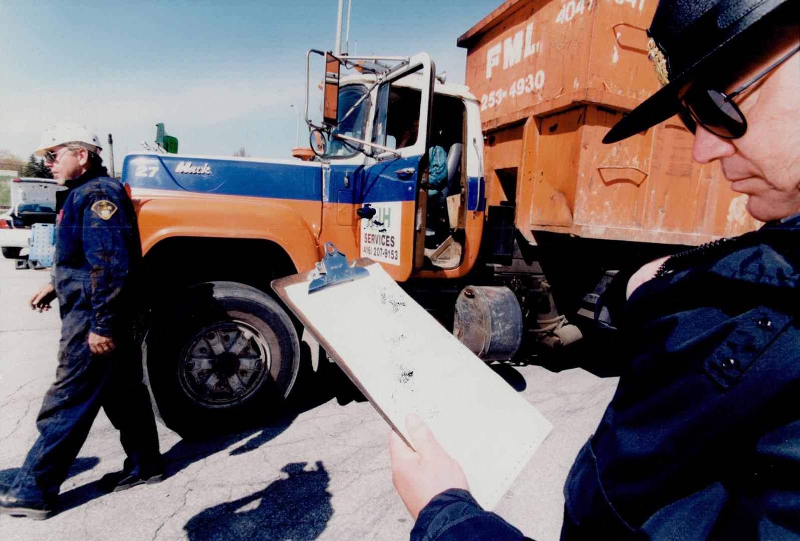 Truck stop: Ontario Provincial Police Sergeant Cam Woolley checks paperwork at truck safety blitz in Toronto yesterday, where 51 per cent of vehicles were faulty