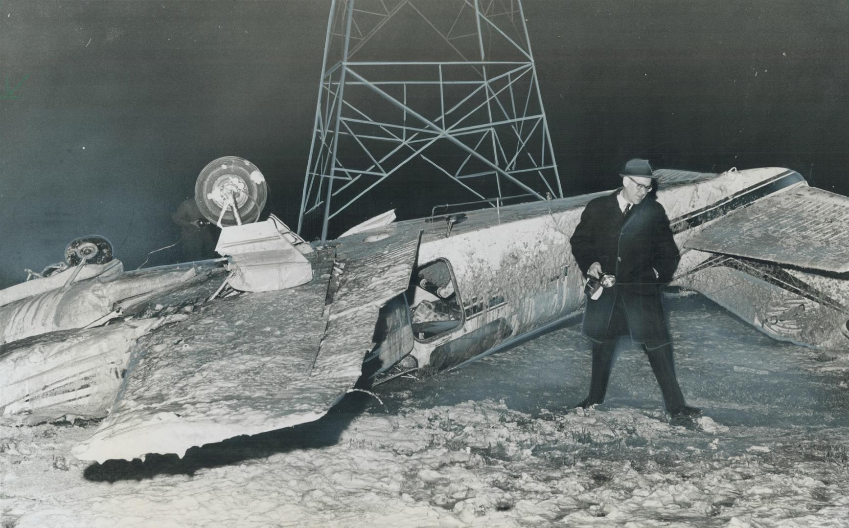 Emergency spotlights outline the scene as Coroner Gerald Blanchet looks over the wreckage of a twin-engine private plane that crashed in Etobicoke's C(...)