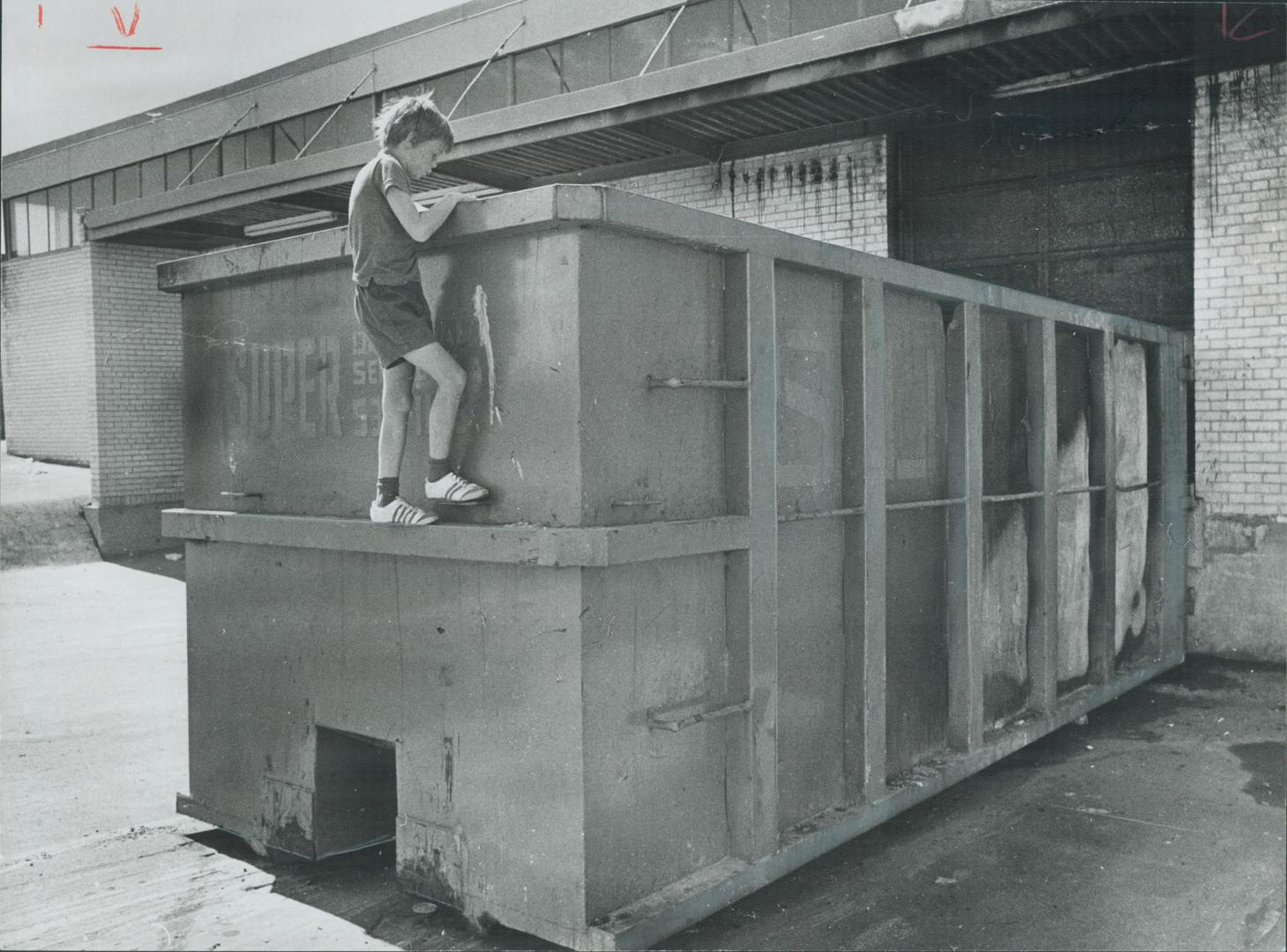 Where garbage caught fire-Gary Bignell, 10, peers into garbage container where 8-year-old Larry Nash of Keele St