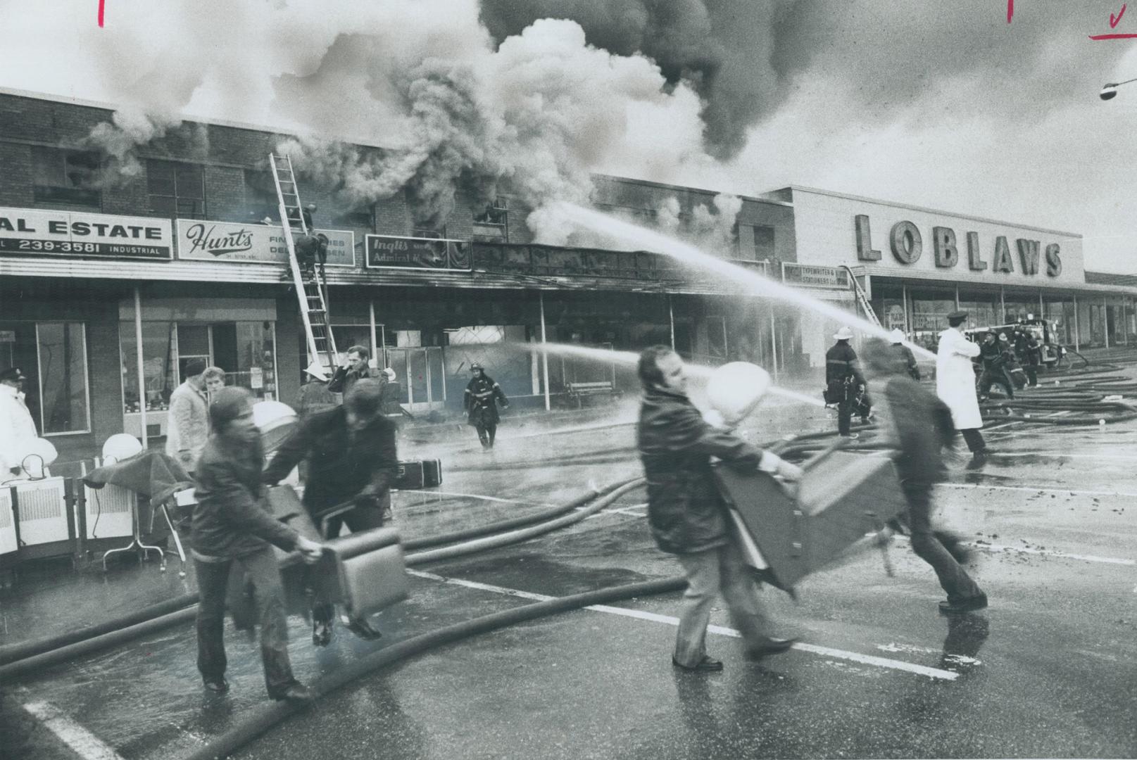 Salvaging furniture as a $750,000 blaze sweeps through Six Points Plaza in Etobicoke, men carry chairs across the parking lot while firemen pour strea(...)