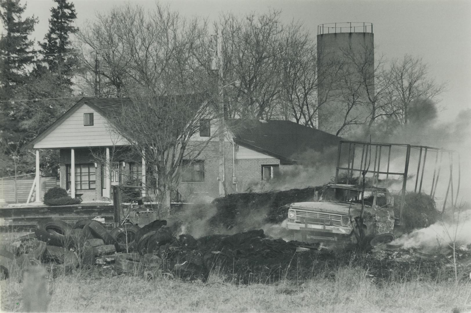 A charred trucks sits surrounded by smouldering tires