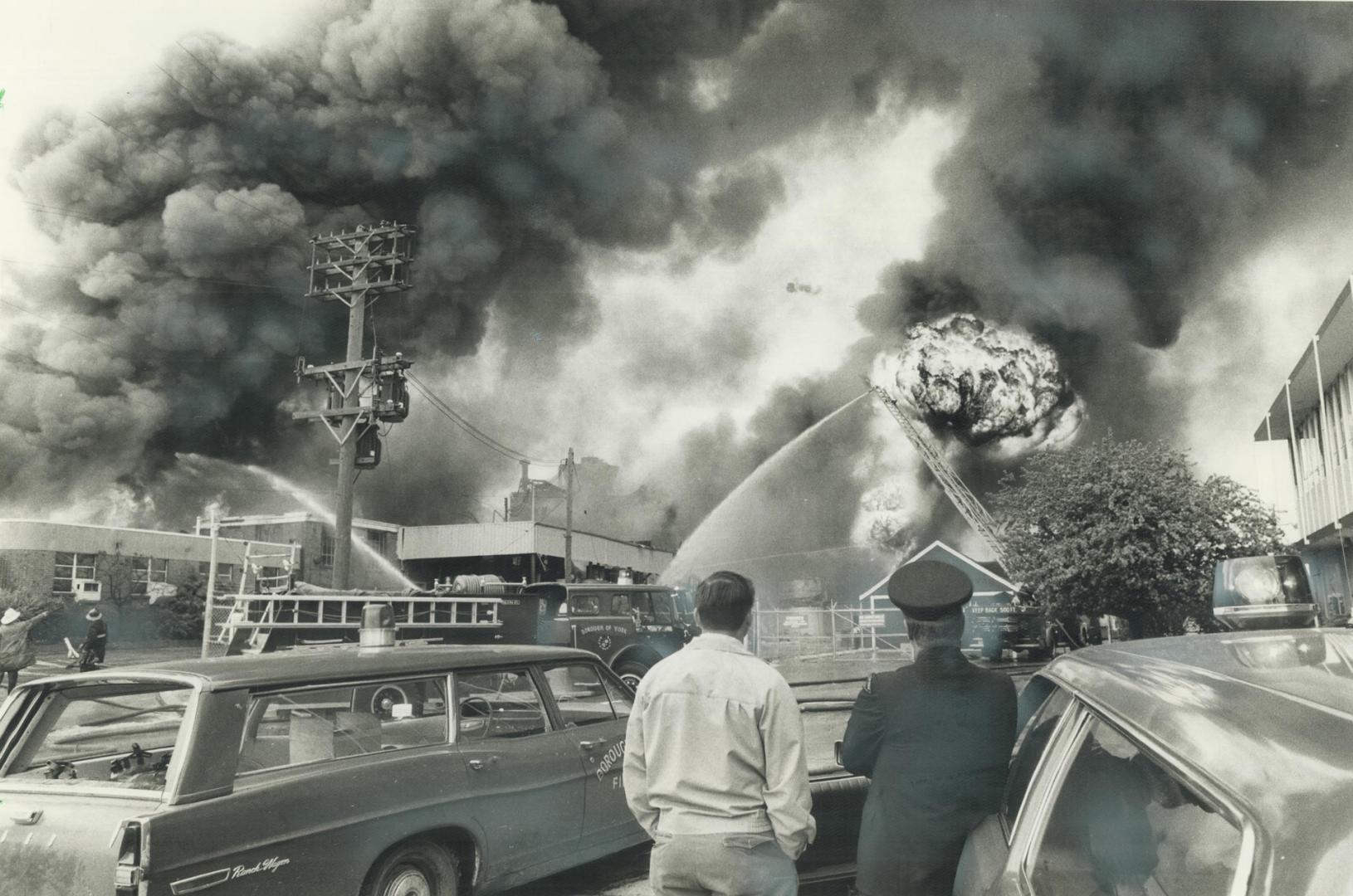 Atop aerial ladder, a fireman continues to pour water on the fire at Ashland Oil Canada s chemical plant despite a drum of volatile solvent exploding (...)