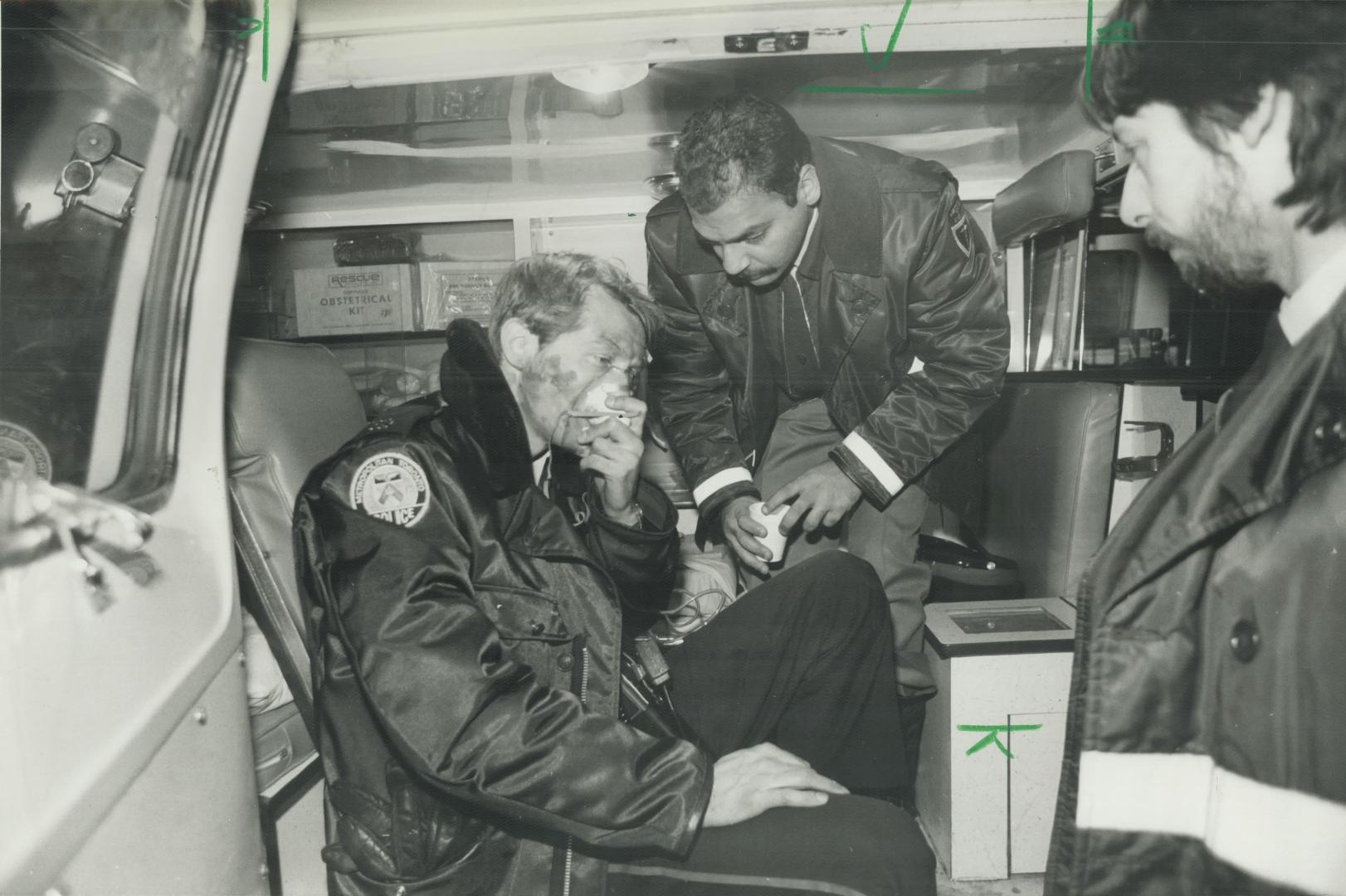 A Metro policeman gulps oxygen as an ambulance attendant helps him