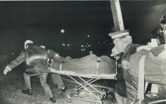 Stretcher bearing body of one of the three Etobicoke firemen killed in fire is rolled away from Kimberly-Clark plant