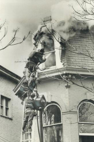 Fire strikes rooming house. Firemen fighting a blaze today on the top floor of a three-storey rooming-house on Pembroke St. carry up a fan to pull out(...)