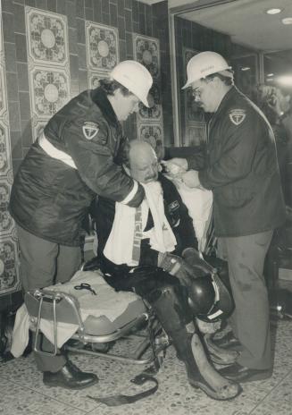 Ambulance attendants help one of several firefighters injured last night fighting a top-floor blaze in a Triller Ave