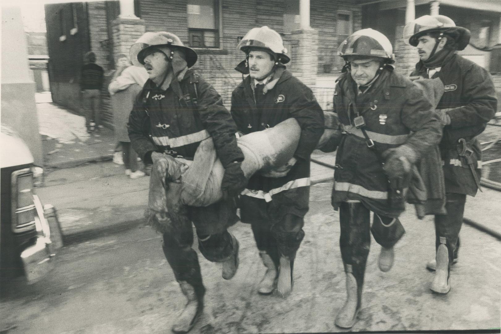 Firefighers run with one of the victims to an ambulance after a morning house fire killed two people and put five others in hospital. Arson is suspect(...)