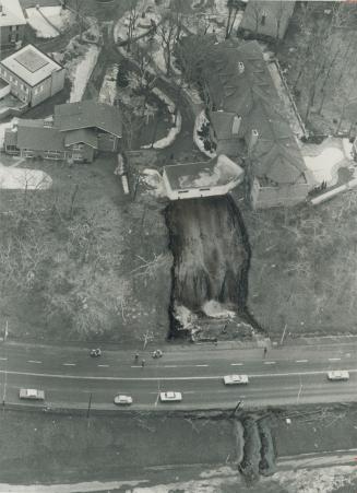 Five-car garage perches precariously on the edge of a 100-foot gorge caused by last night's landslide that dumped mud and trees on to Mt. Pleasant Rd.(...)