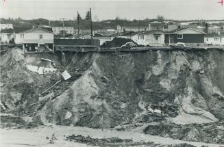 Part of a house teeters on the edge of the chasm created by gigantic mudslide that rolled through the village of St