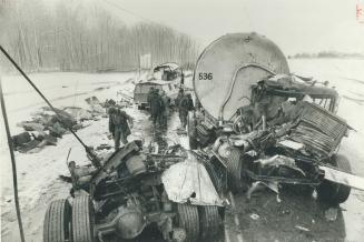 Rear axle of bus lies next to crumpled cab of tanker truck as emergency workers examine Highway 400 crash scene