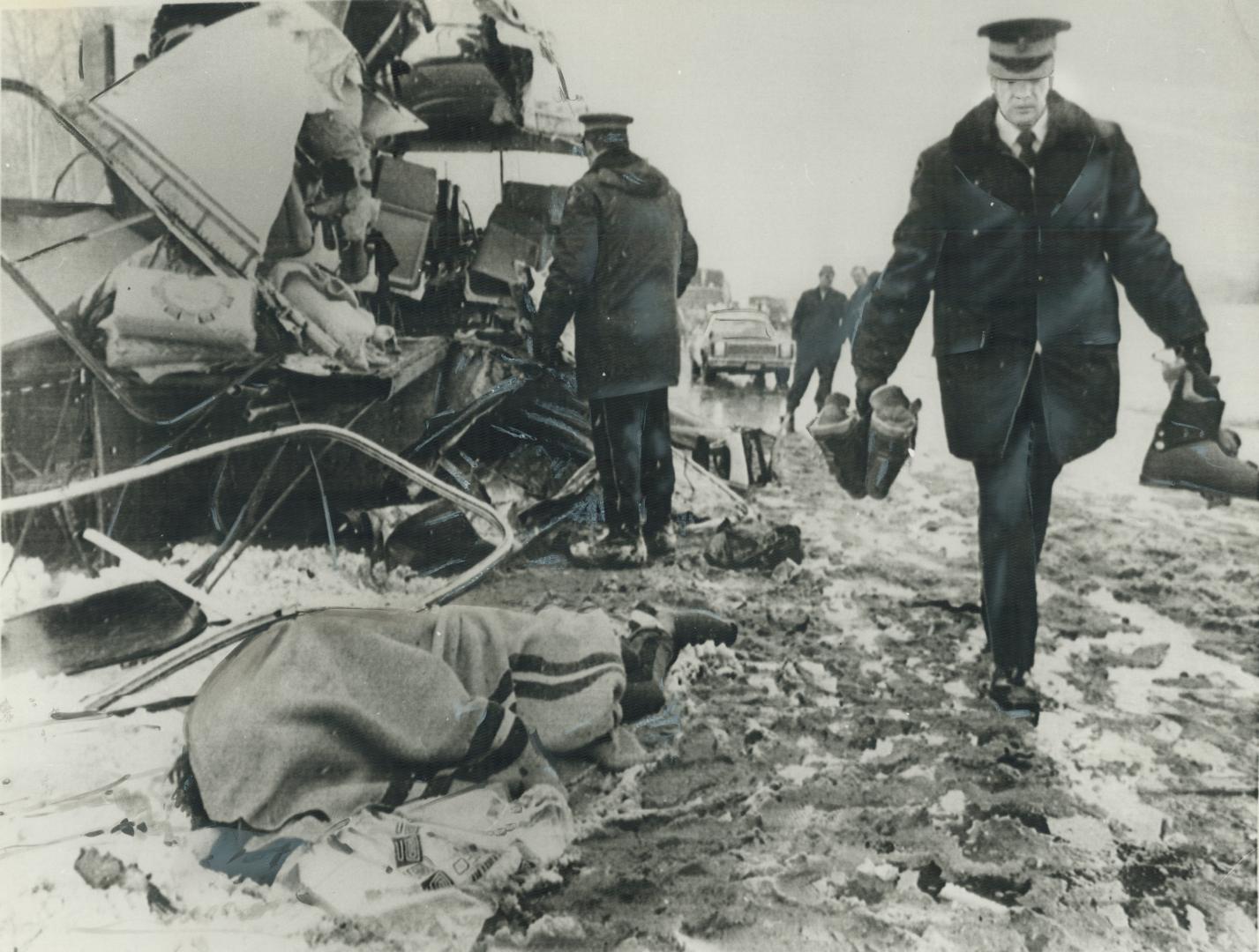 A student's body lies covered with a blanket and a policeman carries ski boots at the scene of carnage