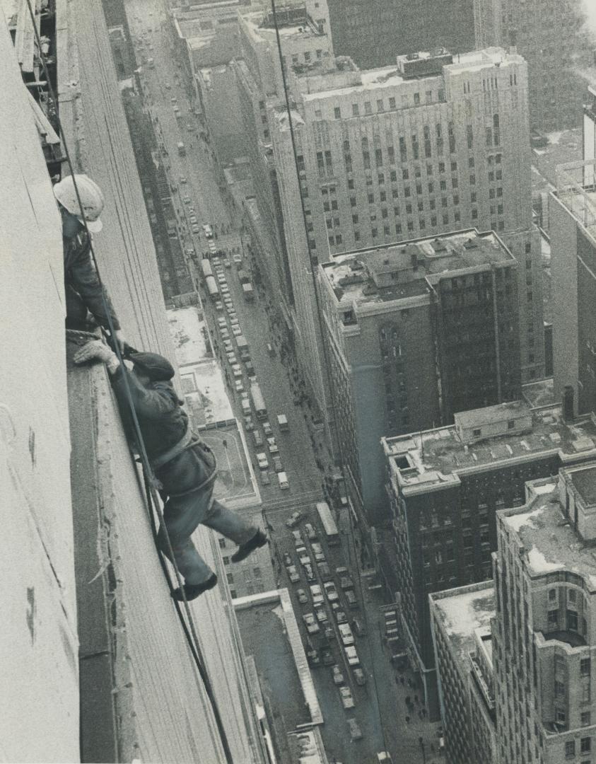 Window cleaner grabs for ledge of 473-foot Simpson's Tower while being hauled by rope to top